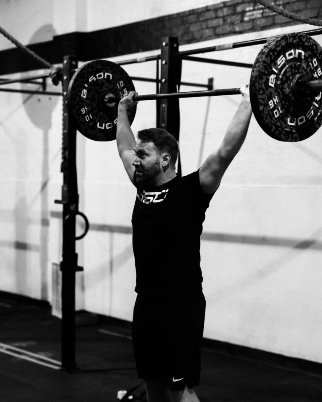 Matt, founder of The Fitness CFO, overhead barbell lift at his CrossFit gym